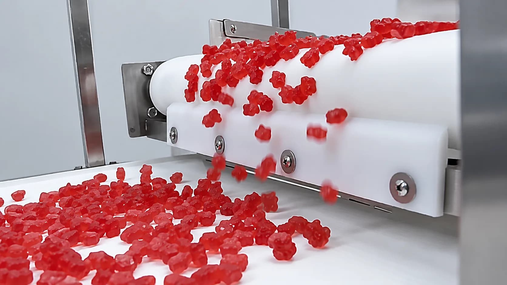 Red gummies moving between white production conveyors